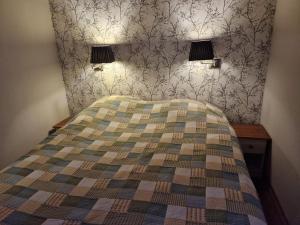 a bedroom with a bed with two lamps on the wall at Villa Vonkale in Äänekoski