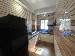 a kitchen with a black refrigerator in a room at Zen Luxe Abode in Siliguri +2 photos