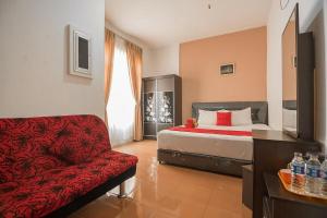 a bedroom with a bed and a red couch at RedDoorz @ Batam Center 2 in Batam Center