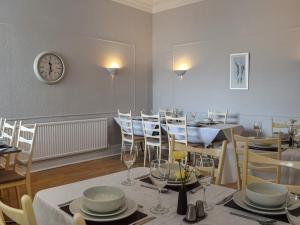 a dining room with tables and chairs and a clock on the wall at Drumford in Blackpool +24 photos