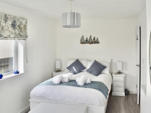 a white bedroom with a bed with blue pillows at Seagulls View in Brixham
