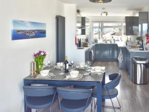 a dining table with blue chairs in a kitchen at Seagulls View in Brixham