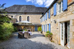a table with an umbrella in front of a building at Le Prieuré La Ferme in Souillac