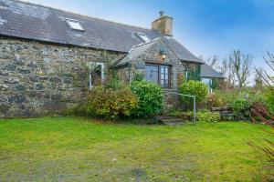an old stone house with a grass yard in front of it at 1 Caerau Isaf in Haverfordwest