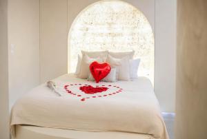a white bed with a red heart on it at La Suite Grecque in Mitry-Mory