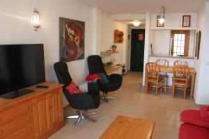 a living room with a television and chairs and a table at Deltamar Solo Familias Serviplaya in Xeraco
