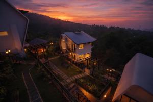 a house with a sunset in the background at Ymoon Mountain Resort Wayanad in Koroth