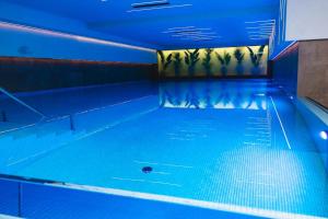 an empty swimming pool with blue lights on the ceiling at Planet Imperial Apartman & SPA in Niš