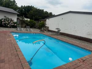 a large blue swimming pool in a yard at No7 Mc Intyre Guest House in Sasolburg