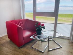 a red chair and a glass table with a potted plant at Apartment Rickmer Rickmers Teichhof Fehmarn in Wenkendorf