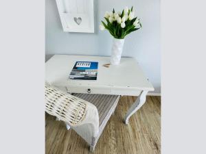 a white coffee table with a vase of flowers on it at Apartment Rickmer Rickmers Teichhof Fehmarn in Wenkendorf +33 photos