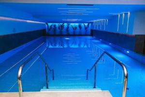 an empty swimming pool with stairs and blue lighting at Planet Residence Royal Studio & SPA in Niš