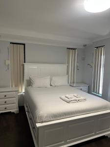 a white bedroom with a white bed and a lamp at Slate House Caversham in Caversham