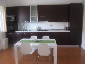 a kitchen with a white table and white chairs at Casa Vacanze Helena in Cava dʼAliga