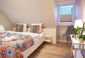 a bedroom with a bed and a table and a window at Südstern OG, Schwalbenweg in Wyk auf Föhr