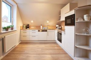 a kitchen with white cabinets and a large window at Südstern OG, Schwalbenweg in Wyk auf Föhr