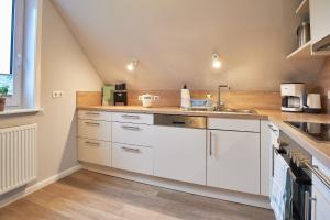a kitchen with white cabinets and a sink at Südstern OG, Schwalbenweg in Wyk auf Föhr +18 photos