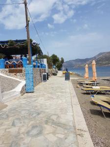a beach with chairs and umbrellas next to the water at Dimitreli Beach House in Telendos