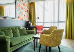 a living room with a green couch and two chairs at Thon Hotel Brønnøysund in Brønnøysund