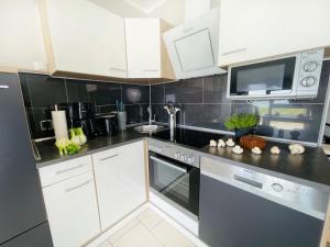 a kitchen with white cabinets and black counter tops at Apartment Potosi Teichhof Fehmarn in Wenkendorf