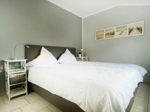 a bedroom with a large bed with white sheets at Apartment Potosi Teichhof Fehmarn in Wenkendorf