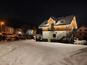 a house with christmas lights on it in the snow at Pienińskie Zacisze in Jaworki