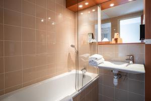 a bathroom with a tub and a sink and a shower at Kyriad Rennes Nord Hotel in Rennes