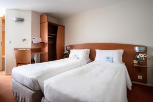 two beds in a hotel room with white sheets at Kyriad Rennes Nord Hotel in Rennes +30 photos
