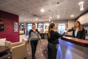 two women standing at a counter in a restaurant at Kyriad Rennes Nord Hotel in Rennes