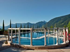 a large swimming pool with trees and mountains in the background at Villa Residence Franziskus in Tirolo