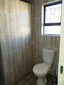 a bathroom with a toilet and a window at Bredell Motel in Bredell