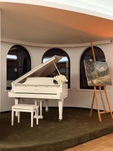 a white piano in a room with a painting at Tieflehner Hof Pitztalhaus Hotel in Sankt Leonhard im Pitztal