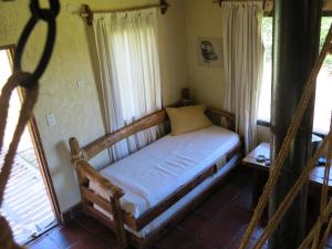 a small bed in a room with windows at Búho Multiespacio in Villa Giardino