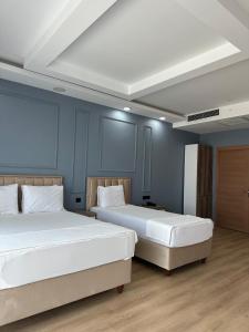 two beds in a room with blue walls at İdil Haznedar Otel in İdil