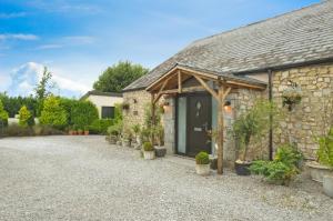 a stone cottage with a black door and potted plants at Tathan Herd in Flemingston