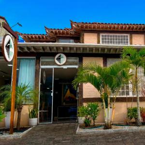 a house with palm trees in front of it at Pousada Ilha Branca Centro in Búzios