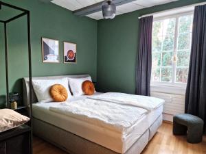 a bedroom with green walls and a bed with orange pillows at FEWOCASA Central Family Apartment Rorschach - Lake Constance - Near St Gallen in Rorschach