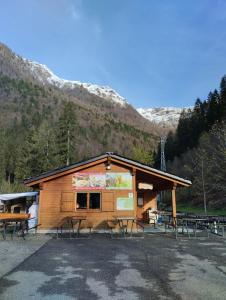 a cabin with picnic tables in front of a mountain at Dormire a Valgoglio Baita della Diga in Valgoglio