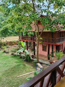 a house with a balcony and a tree at A Vũ Homestay & Coffee in Kon Cho Dri +10 photos