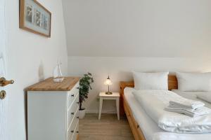a small bedroom with a bed and a night stand at Haus Arfsten "Elena", Nieblum in Nieblum