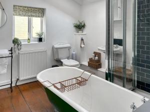 a bathroom with a tub and a toilet and a sink at Time Cottage in Coltishall +3 photos
