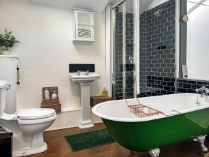 a bathroom with a green bath tub and a toilet at Time Cottage in Coltishall