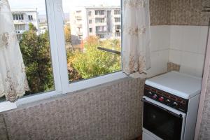 a kitchen with a stove and two windows at APARTAMENTS Verkvebi in Gori