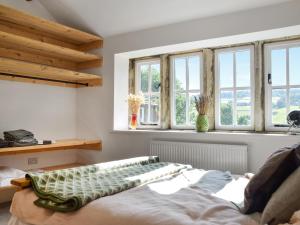 a bedroom with windows and a bed in it at Kestrel Cottage in Holmfirth