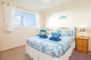 a bedroom with a bed with blue pillows and a window at Ty Peggie in Haverfordwest