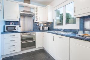 a kitchen with white cabinets and a sink and a microwave at Ty Peggie in Haverfordwest +26 photos