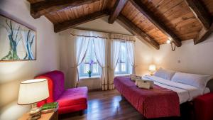 a bedroom with a large bed and two red chairs at Villaggio Turistico Ploner in Carbonin +23 photos