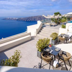 a patio with a table and chairs and the ocean at Andromeda Villas & Spa Resort in Imerovigli