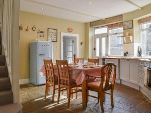 a kitchen with a table and chairs and a refrigerator at St Georges Cottage in Holmfirth