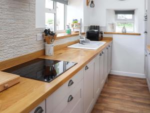 a kitchen with white cabinets and a wooden counter top at Rhoshill in Llanfyrnach +20 photos